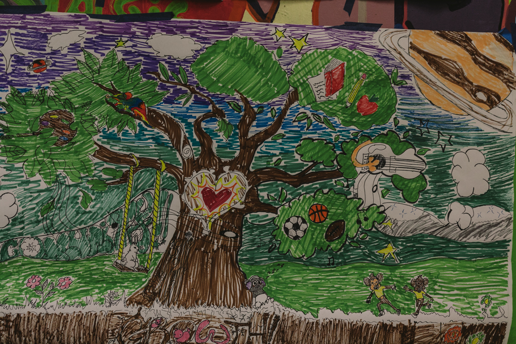 A colorful concept sketch for a mural showing animals playing under a tree with a red heart over the center of it's trunk.