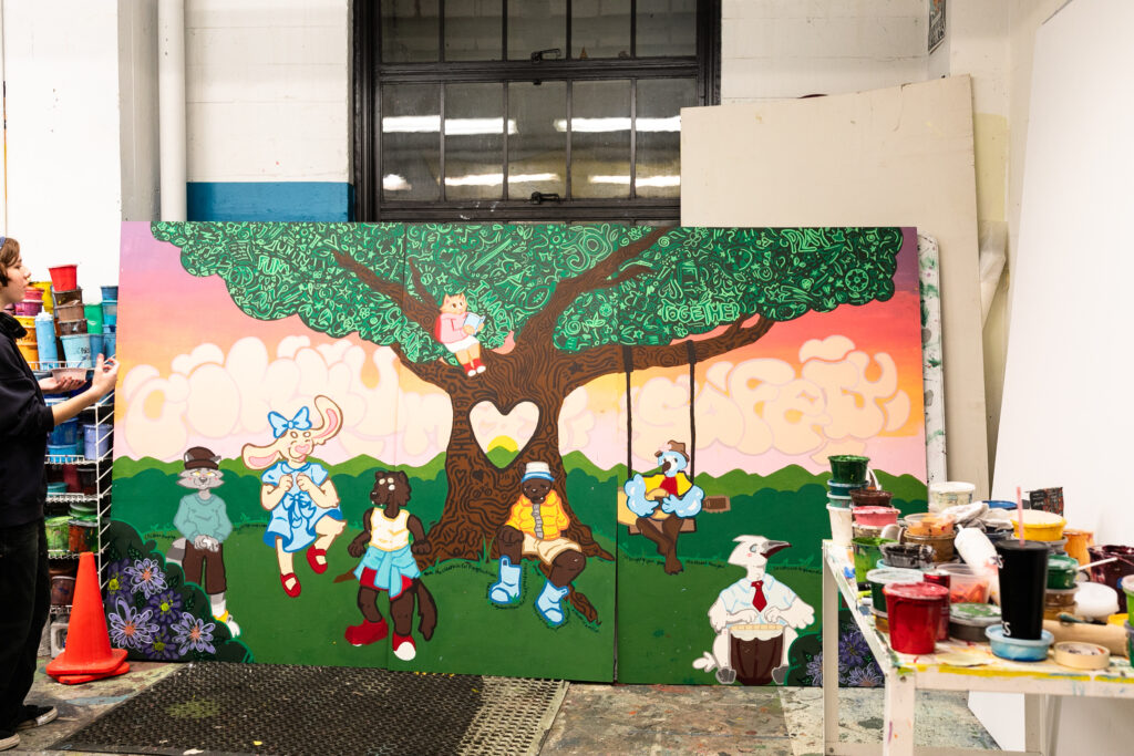 A wide view of the completed mural -- showing a group of cartoon animals gathered under a broad tree -- inside the Urban ArtWorks studio before it was hung at Broadview.