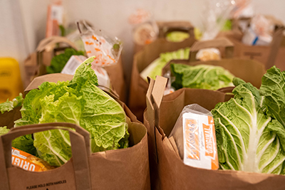 Rows of brown paper bags filled with English muffins, iceberg lettuce, and other groceries.