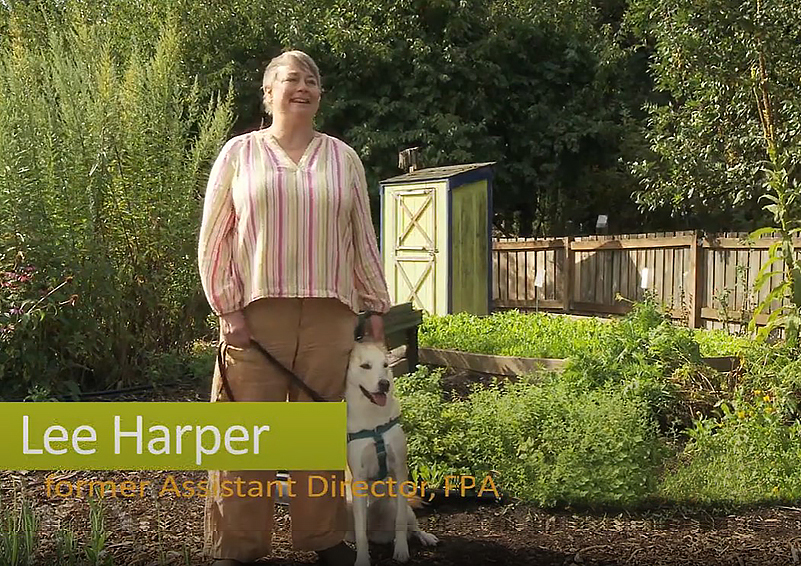 A smiling woman with short brown hair wearing tan pants and a yellow-and-pink-striped blouse stands in a farm setting. Her white dog leans against her leg. Titling reads Lee Harper, former Assistant Director, FPA.