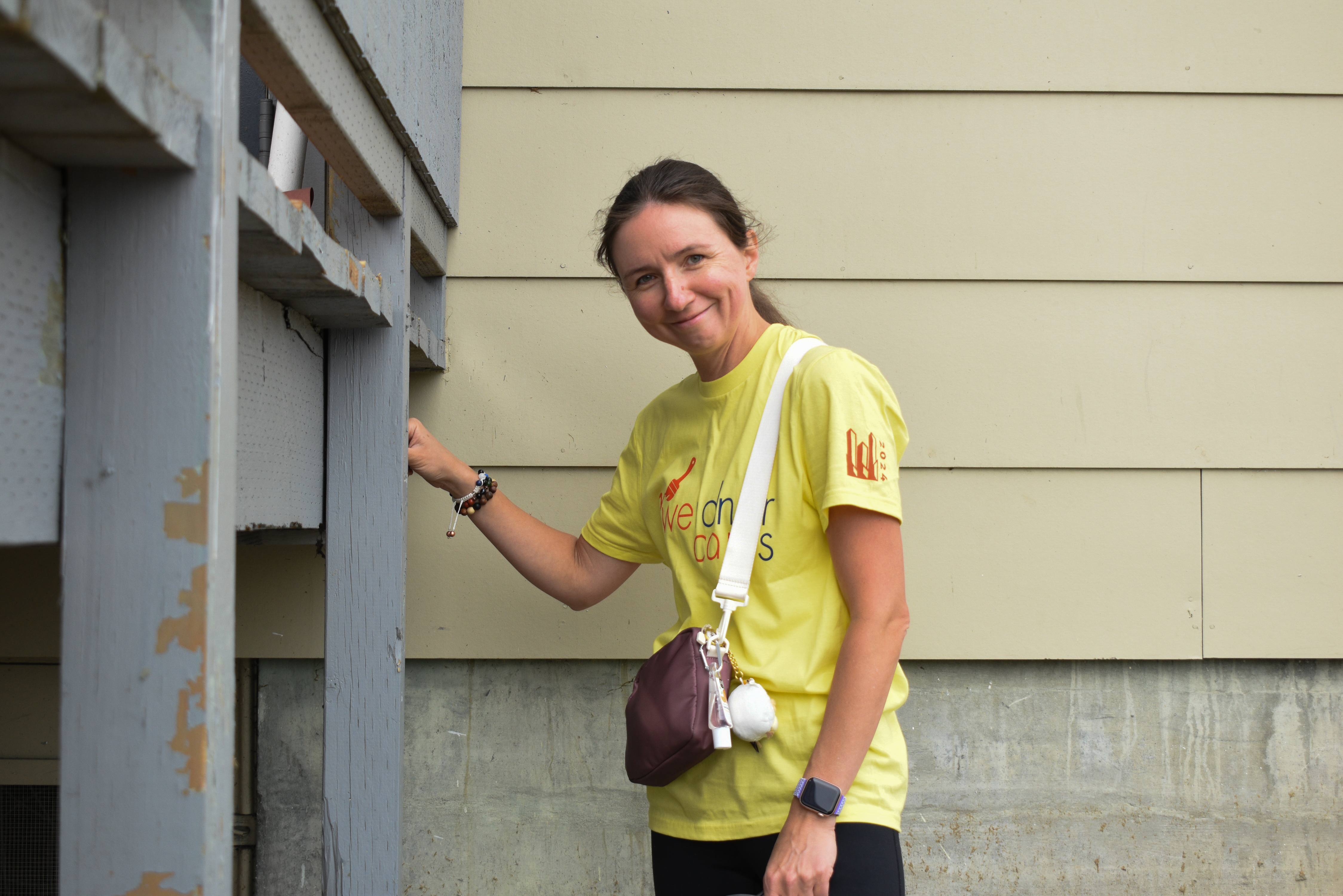 A volunteer in a yellow shirt smiles at the camera