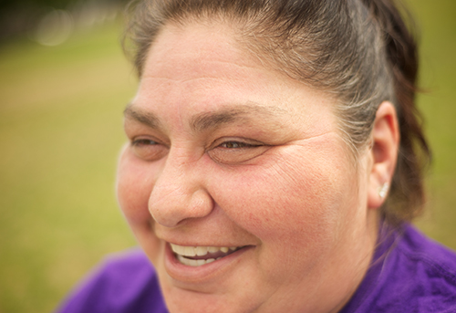 A closing up of the face of a smiling women wearing a purple tshirt