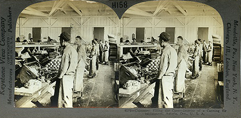 Sepia-toned historical photograph of men lined up at a bench in fish cannery.