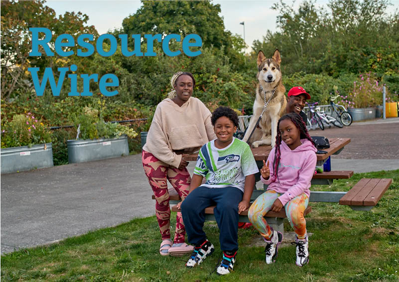 A family of four sits around a picnic table with their dog, a husky, sitting at attention on top. The words Resource Wire appear besides them.