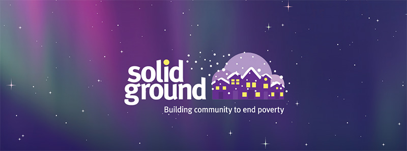 An illustration of Solid Ground's logo, comprising several purple houses with lit windows and snow-covered roofs, over a purple-hued night sky.