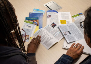 The hands of two people rest on a table covered with brochures and tenant services information.