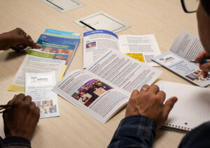 The hands of two people rest on a table covered with brochures and tenant services information.