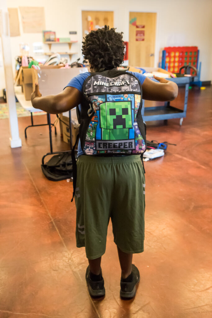 A small child with his back to the camera shows off his new Minecraft backpack.