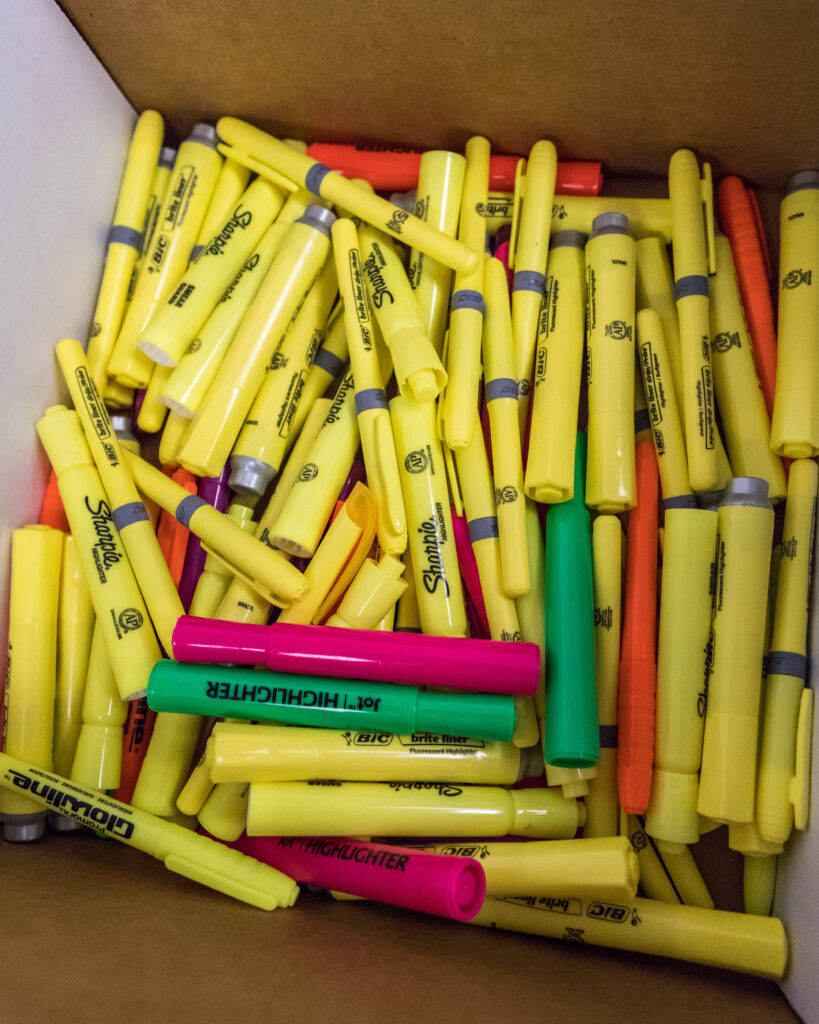 A box full of yellow Sharpie highlighters, with a few pink, green, and orange ones mixed in.