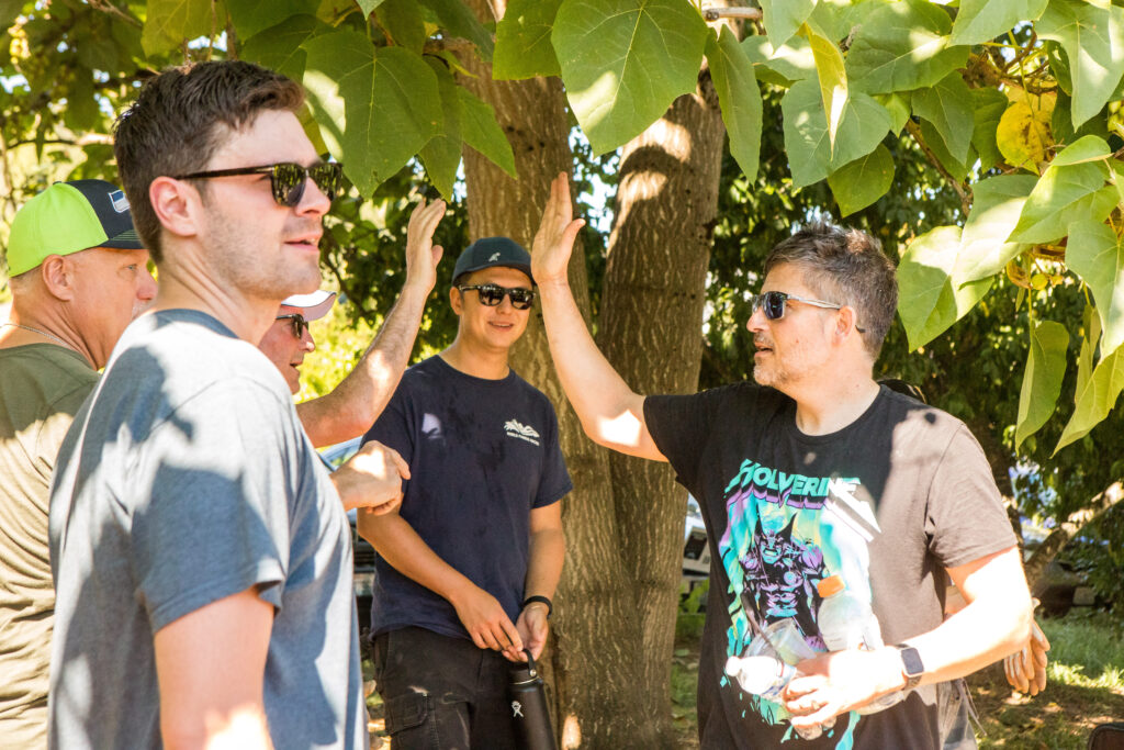 Several volunteers rest in the shade of a tree.