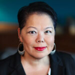 Headshot of a woman with short black hair wearing a black blazer.
