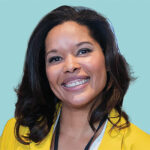 Headshot of a smiling woman with brown hair wearing a bright yellow blazer on a light blue background.