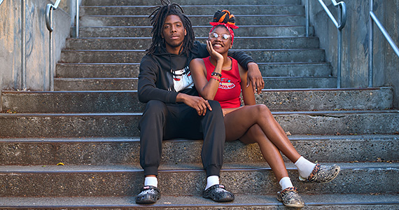 A young couple wearing black and red pose on a concrete staircase, smiling.