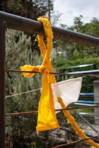 A yellow cloth twisted and slung over a fence