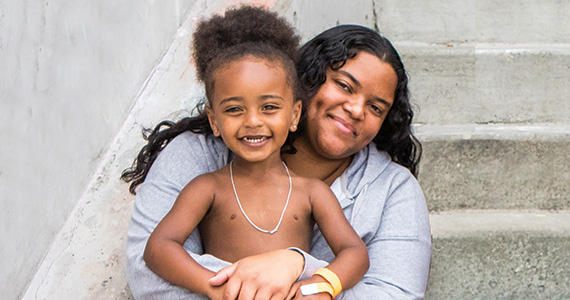 A mom hugs her son. They're sitting on a set of concrete steps.