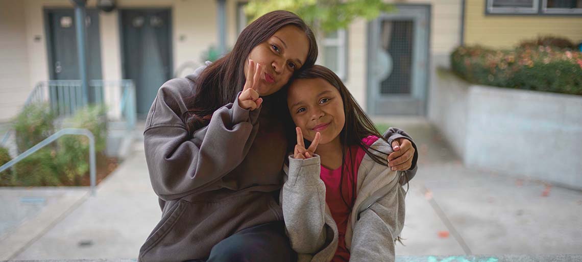 A mom and daughter pose, making peace signs.