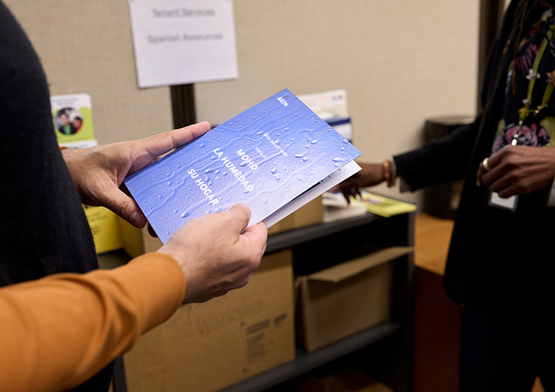A man holds a booklet about mold written in Spanish.