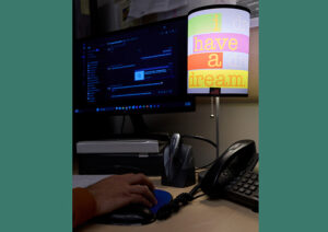 A dark computer monitor, a man's hand on a mouse, and a colorful lamp reading 'I have a dream.'