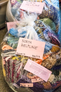 Large plastic bags filled with knitted items, some of them labeled "North Helpline."