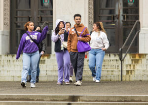 A group of people walk away from a building with two sets of very large double doors.