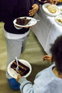 A close up of two slices of cake on held in paper plates.