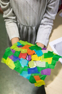 A child's hands holding out a trapestry of colorful pieces of paper.