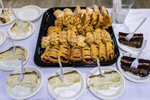 A tray of pastries surrounded by small plates with a slice of cake on each one.