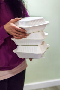 A close up of someone's hands holding a stack of three to-go containers.