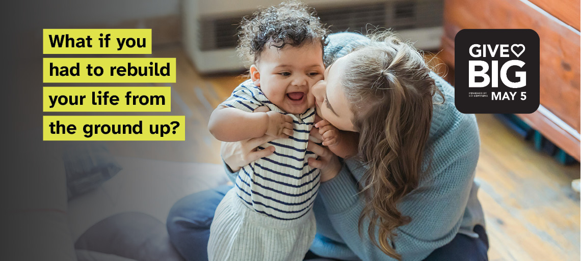 Photo of a mom with dirty blonde hair and a light blue sweater and jeans, sitting on the floor kissing her baby's cheek. The baby has curly black hair and wears a blue and white striped shirt. Black text on bright yellow background reads: What if you had to rebuild your life from ground up?