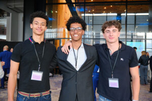 Three smartly dressed young men with arms around each other posing for photo
