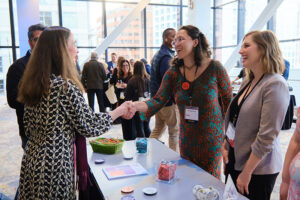 Two women shaking hands across a table