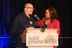 Two people behind a podum that says Solid Ground