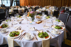 A round table dressed with table clothe, place settings, and salads.