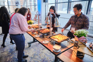 People selecting appetizers from a long table of food