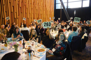 Several people holding up bid cards in a crowded ballroom