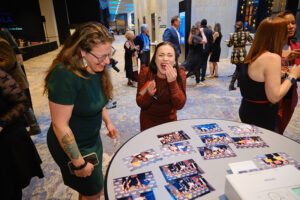 Two people laughing while looking at a table covered with photographs