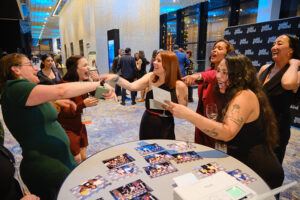 Several peole pointing at each other and laughing infront of a table of photographs