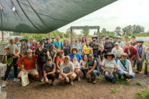 A large group of volunteers posing for a group photo in front of a sign that says "Solid Ground's Giving Garden."