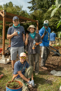 A bunch of volunteers working to pull weeks from vegetable beds.