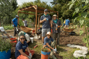 A bunch of volunteers working to pull weeks from vegetable beds.
