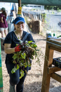 A woman holding a bunch of freshly harvested beets.