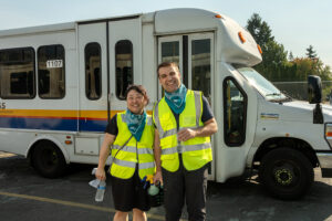 Two people in reflective vests infront of a paratransit bus