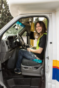 A volunteer sitting in the cab of para transit bus.
