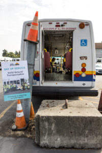 A sign advertising Solid Ground's Day of Service next to the open rear door of a paratransit bus.