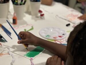 Close up of the hands of a child painting a fabric square