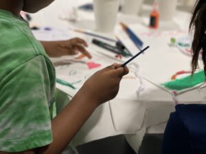 Close up of the hands of a child painting a fabric square